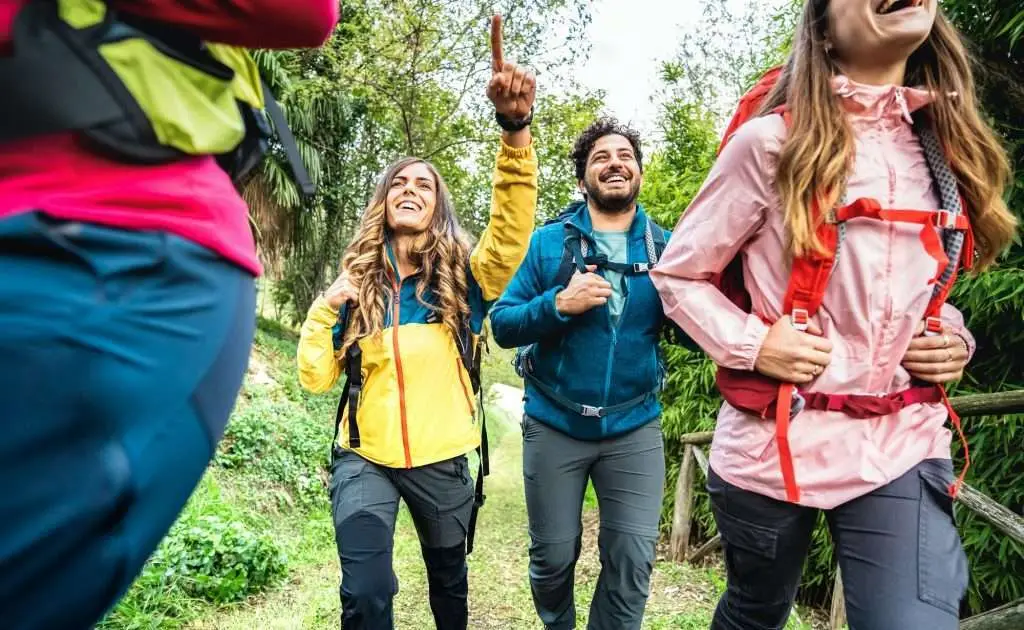 Front view of friends group trekking in forest on italian alps