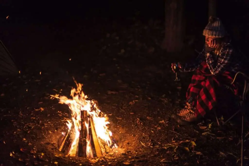 Woman sitting by campfire at night